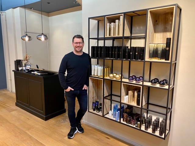 Volkert in de salon naast de wand met haarproducten