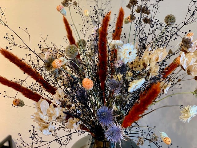 Boeket droogbloemen in de salon met roestbruine pluimen en blauwe distels