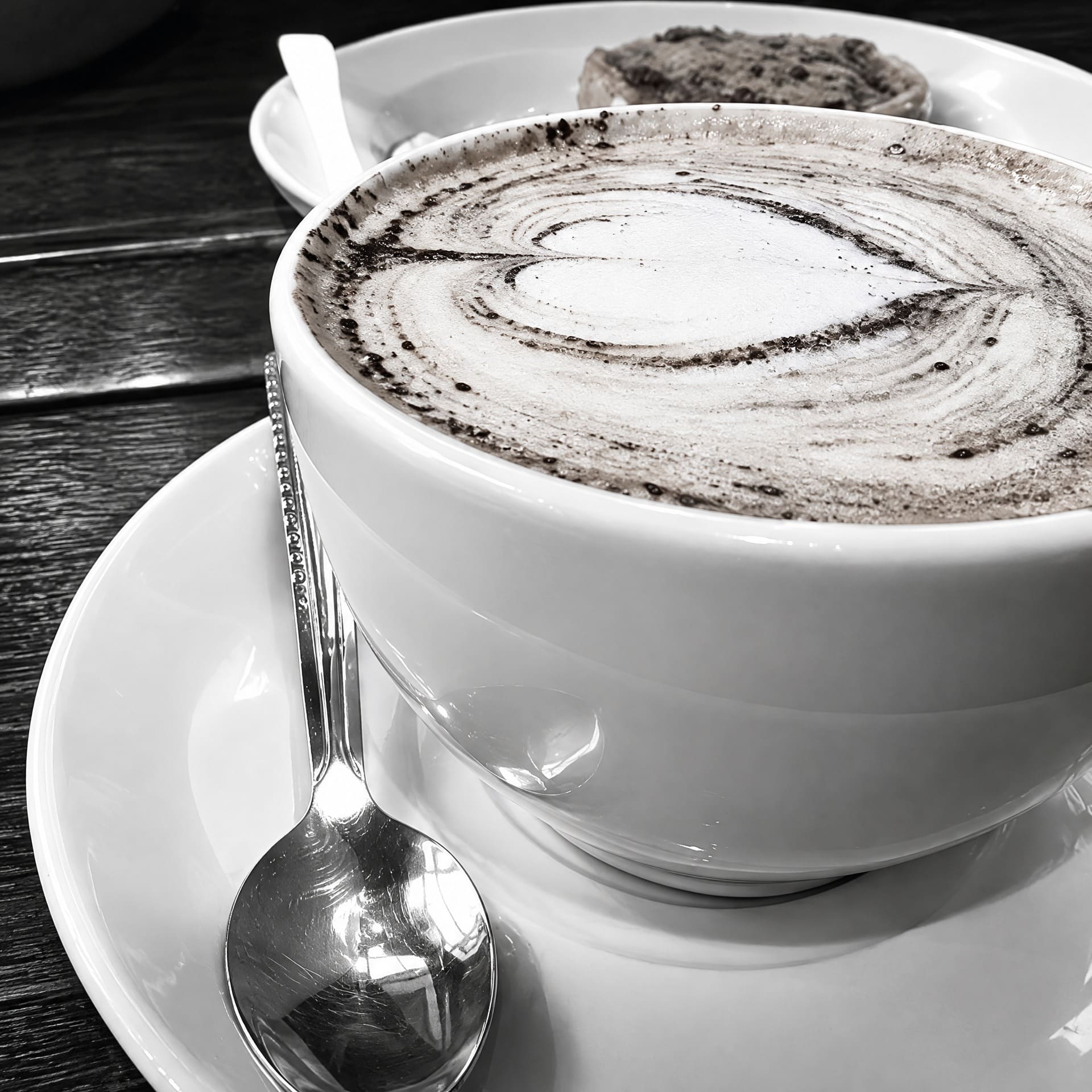 Kop cappuccino met een hart in het schuim, op een schoteltje met een lepel